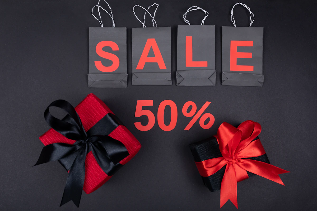 Black shopping bags spelling SALE above a red 50% sign and two gift boxes tied with ribbons